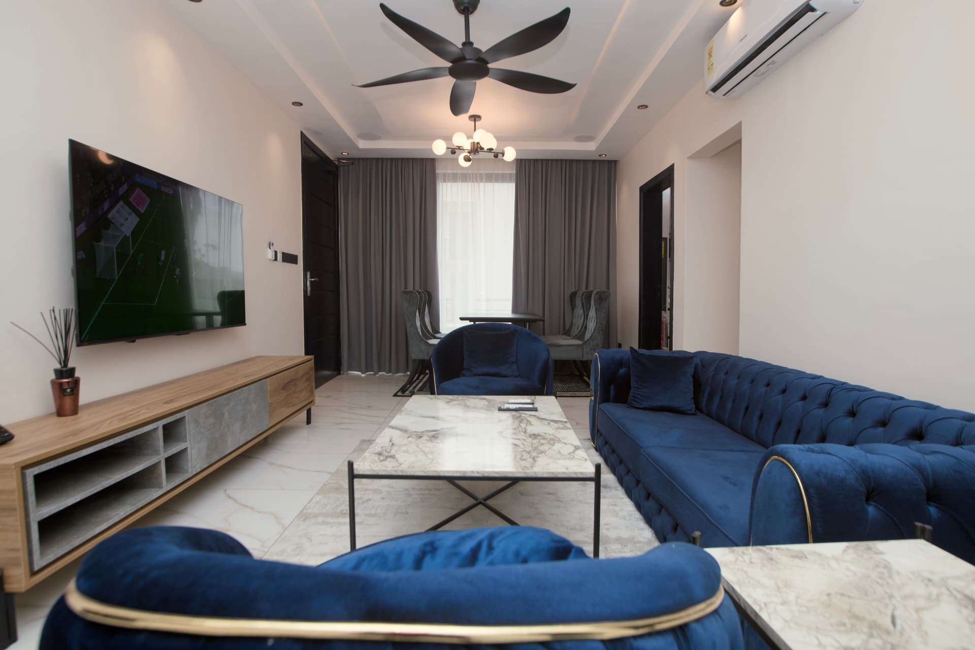 Family Residence living room with blue velvet seating, marble coffee table and dining area
